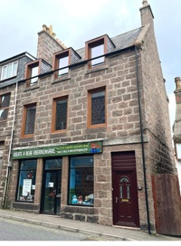 Picture showing tall building with shop and a separate front door to building at side of shop