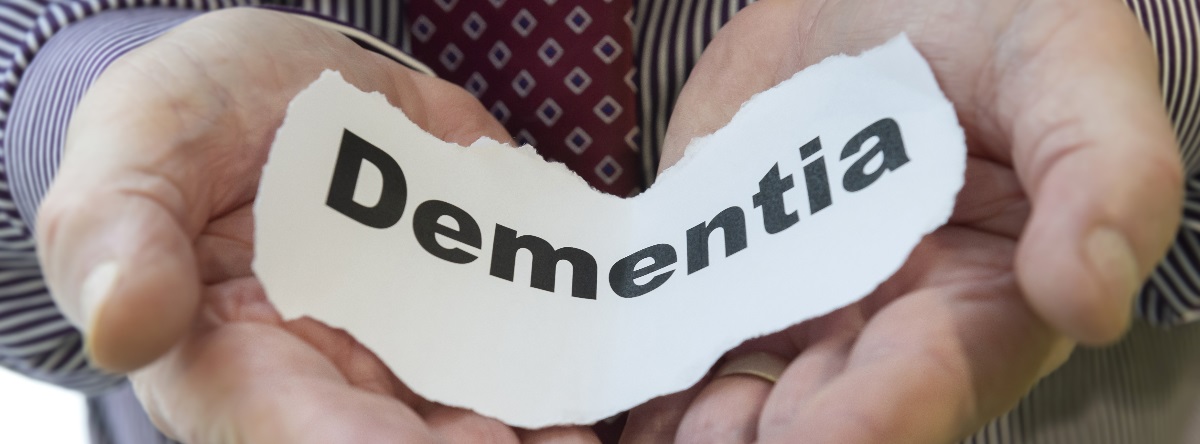 Hands holding a piece of paper with Dementia written on it