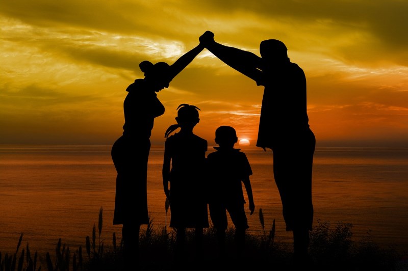 Family with two children holding hands with sunset behind them