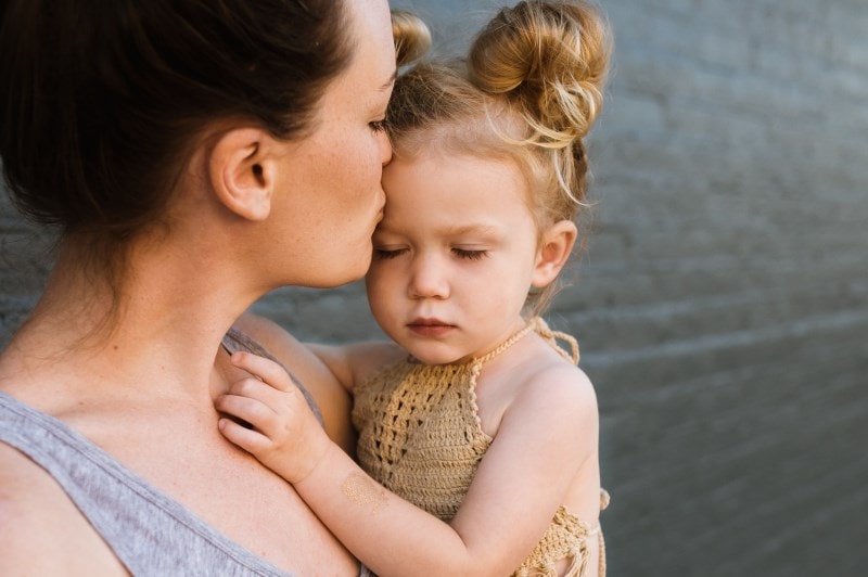 Mother hugging and kissing her daughter