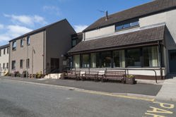 View of Eigie House with three benches in front of building with large windows