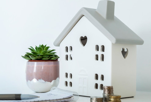 Close up of a tealight house with stacked up coins on a side