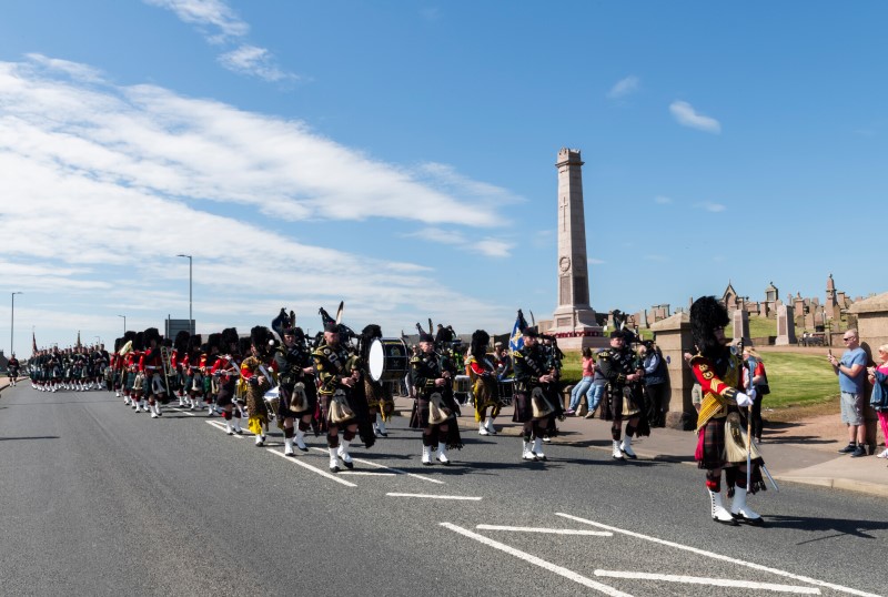 The Scots Regiment on parade with bagpipes and drums in Peterhead as it passes the war memorial on the town's South Road