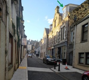 Street view looking down lane with cars parked on both sides of street