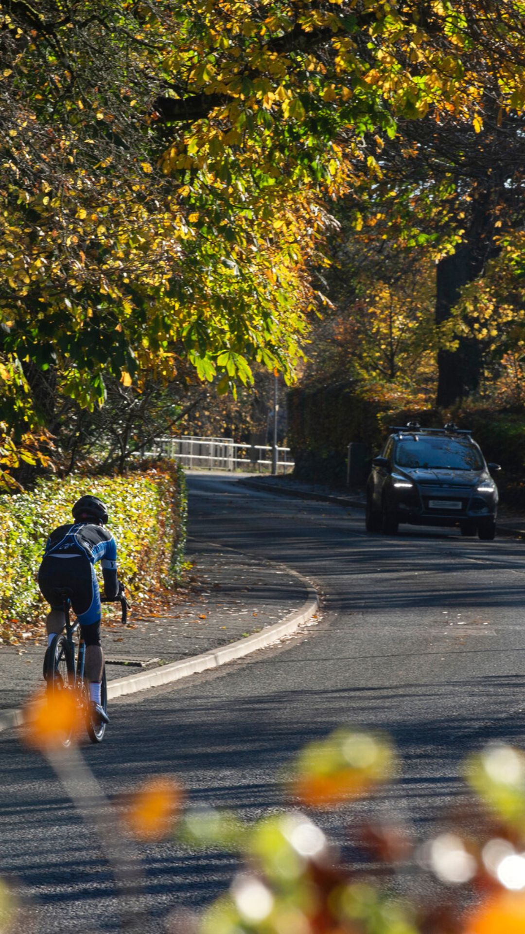 A cyclist approaching a corner with a car approaching form the opposite direction.