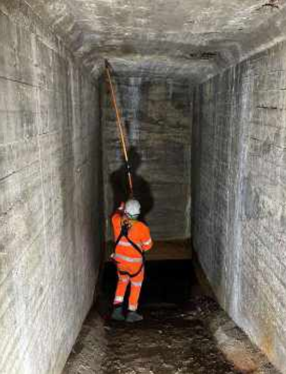 A specialist contractor in orange overalls and white hard hat undertakes concrete quality testing inside Aboyne Bridge