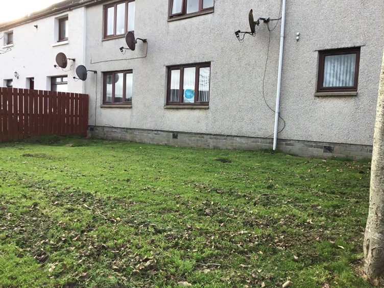 Front of the building at 46 Pitfour Court with grass and fence to the side