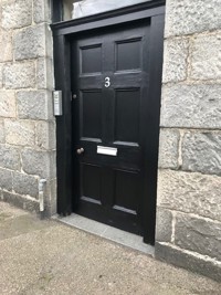 Front of the building with black door and buzzer