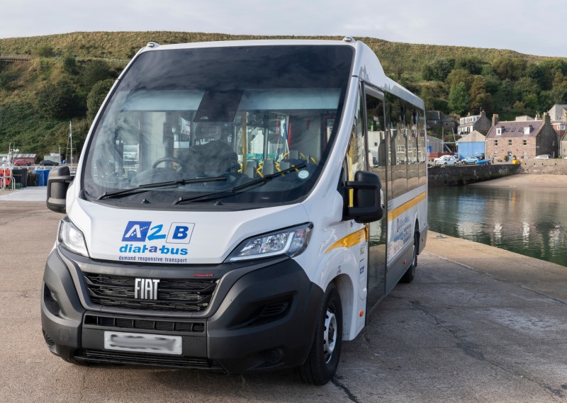 A picture of a white A2B dial a bus with blue decals at a harbour