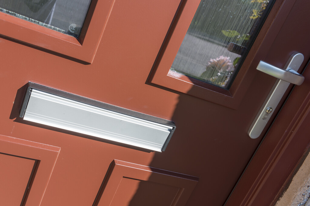 A close up photo of a red door. The door has two clear glazed panes, with a silver coloured handle and letterbox. 